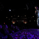 Chris Rock standing on a stage in Brooklyn surrounded by a laughing audience.